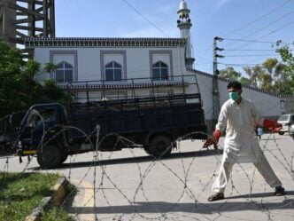 a plain clothes policeman wearing a facemask seals off a street with barbed wire at a residential area in islamabad as a preventive measure against the covid 19 photo afp file